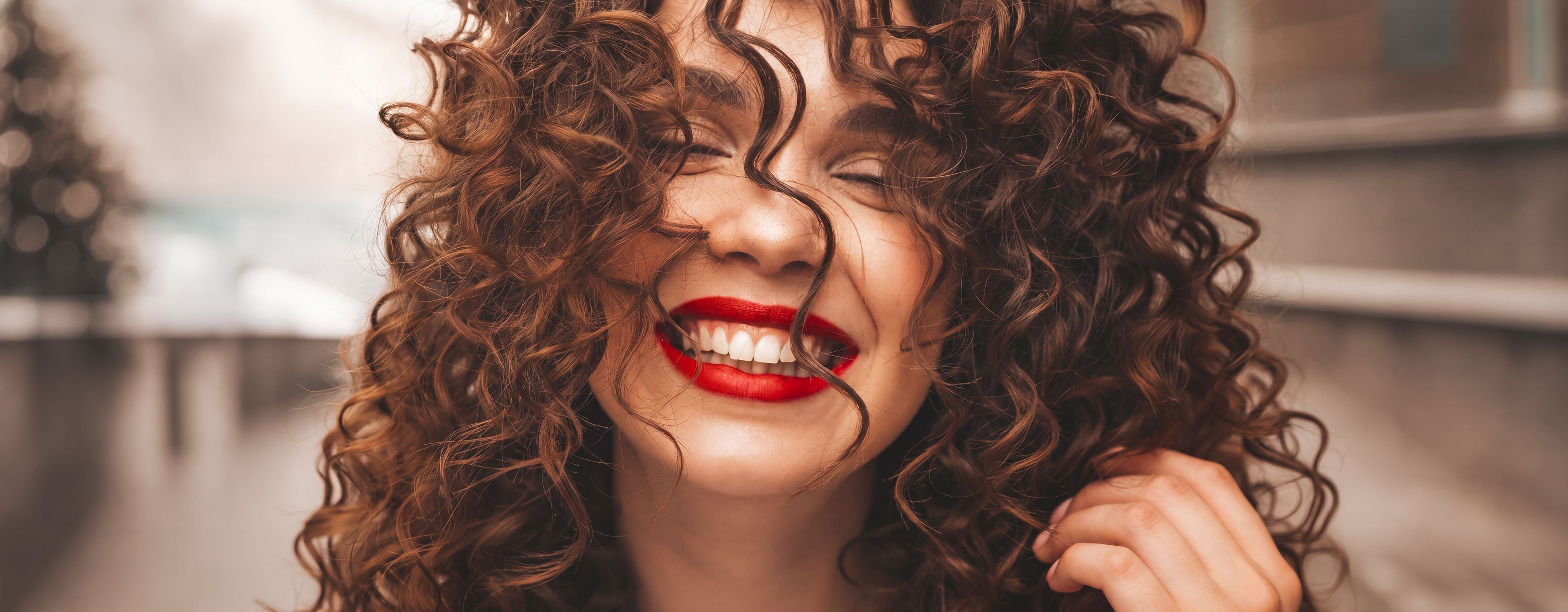 Woman smiling and touching her curly hair 